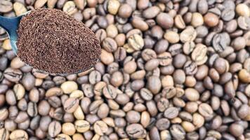 jord kaffe pulver i en metall sked i de förgrund, mot de bakgrund av rostad aromatisk kaffe bönor. kaffe begrepp. foto
