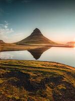 Kirkjufell vulkanisk berg reflektera på sjö i de morgon- på island foto