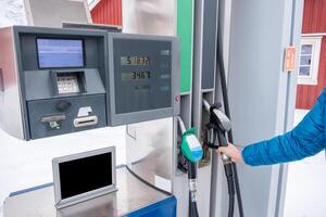 hand höjning bränsle munstycke med självbetjäning i gas station foto