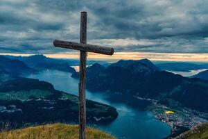 trä- korsa på topp med lynnig himmel utsikt sjö lusern på fronalpstock, schweiz foto