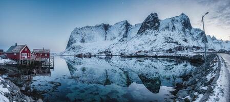 panorama av fiske by på kustlinje och snöig berg räckvidd i vinter- på dyster dag på lofoten öar foto