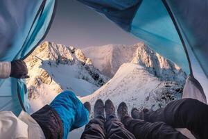 grupp av klättrare är inuti en tält med öppen för se av häftig snöstorm på berg foto