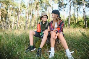 pojke och flicka gå vandring med ryggsäckar på skog väg ljus solig dag foto