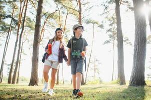 pojke och flicka gå vandring med ryggsäckar på skog väg ljus solig dag foto