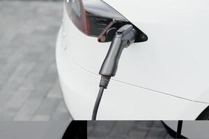 stänga upp av de hybrid bil elektrisk laddare station med kraft tillförsel pluggas in i ett elektrisk bil varelse laddad. foto