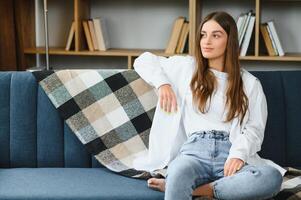 porträtt skön ung kvinna koppla av på soffa i levande rum interiör foto