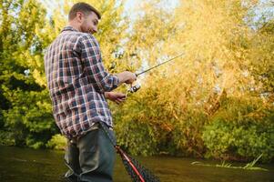 man med fiske stång, fiskare män i flod vatten utomhus. fångst öring fisk i netto. sommar fiske hobby foto