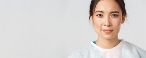 covid19, coronavirus sjukdom, sjukvård arbetare begrepp. närbild av hoppfull utmattad, leende asiatisk kvinna läkare ta av personlig skyddande Utrustning, ha hud märken från respirator foto