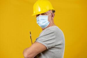 porträtt av en arbetstagare med gul hjälm och skyddande mask för covid foto