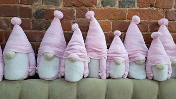 en söt familj av skäggig dvärgar i rosa hattar sitter mot en tegel vägg foto