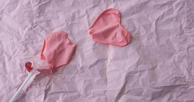 en rosa hjärta boll på en pinne har brista och lögner på en bakgrund av rosa skrynkliga papper. en plats för din text foto
