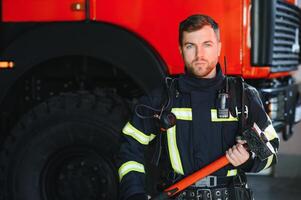 Foto av ung brandman med slägga i händer nära brand motor