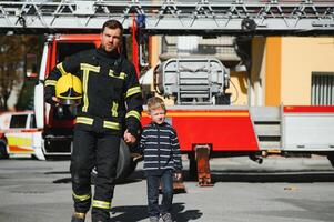 brandman innehav barn pojke till spara honom i brand och rök, brandmän rädda de Pojkar från brand foto