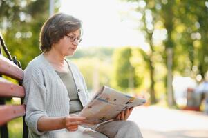 vuxen kvinna Sammanträde i parkera och läsning tidningar. foto