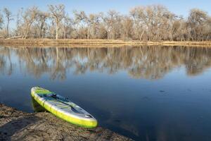 uppblåsbar stå upp paddelbräda på en sjö i tidigt vår - utsikt dammar, ett av natur områden längs de poudre flod i fort collins, colorado foto