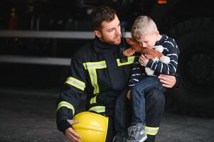brandman innehav barn pojke till spara honom i brand och rök, brandmän rädda de Pojkar från brand foto