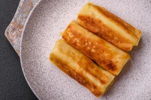 utsökt friterad pannkakor med fyllning rullad på en mörk betong bakgrund foto