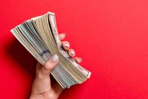 topp se av kvinna hand innehav en tjock packa av annorlunda dollar räkningar på färgrik bakgrund. lön och lön begrepp med tömma Plats för din design foto