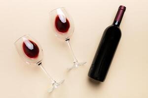 glas av röd vin och en flaska på färgad tabell. platt lägga, topp se med kopia Plats foto