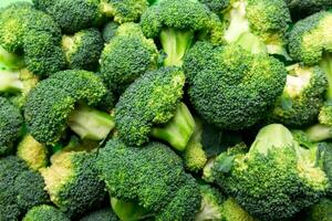 grön färsk broccoli bakgrund stänga upp på färgad tabell. grönsaker för diet och friska äter. organisk mat foto