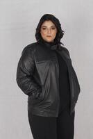 en kvinna i en svart läder jacka och svart byxor foto