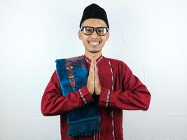 asiatisk muslim man bär glasögon leende till ge hälsning under ramadan och eid al fitr firande över vit bakgrund foto