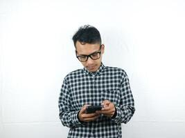 porträtt av asiatisk man innehav mobil telefon läsning, skriver meddelande med fokus ansikte uttryck. foto