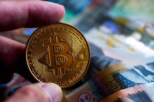 investering i BTC brytning, hand innehav bitcoin kryptovaluta mynt på australier dollar sedlar foto