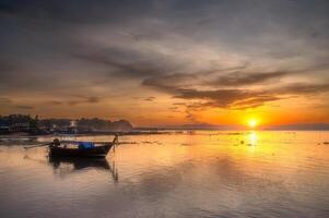 morgon- soluppgång med traditionell lång svans båtar och fiske by bakgrund i sydlig thailand foto