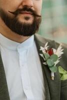 porträtt av leende brudgum med skägg i grå Färg kostym foto