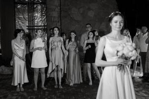 brud i en vit klänning kastar en bröllop bukett foto