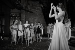 brud i en vit klänning kastar en bröllop bukett foto