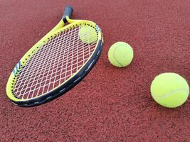 gul tennis bollar och racketen på hård tennis domstol yta, topp se tennis scen foto