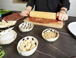 värdinna framställning carpaccio i Hem kök med färsk Ingredienser på svart marmor foto