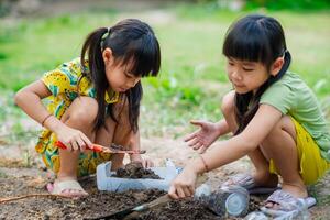 liten flicka plantering växter i kastruller från återvunnet vatten flaskor i de bakgård. återvinna vatten flaska pott, trädgårdsarbete aktiviteter för barn. återvinning av plast avfall foto