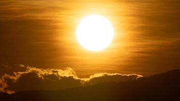 närbild av ljus stor Sol på de himmel med orange lutning färger i en lugnt kväll. foto