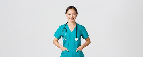 covid19, sjukvård arbetare, pandemi begrepp. självsäker leende Söt asiatisk kvinna läkare, läkare ser fast besluten och optimistisk, innehav händer i fickor av skrubbar, undersöka patienter i klinik foto