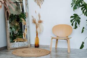 interiör skott. ljus rum av de studio. där är en vas med pålar av vete intressant trä- tabell. de huvud element av de rum en korg- matta. golv spegel och trä- stol. foto