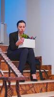 arbetslös affärskvinna innehav låda av grejer på företag trappa efter vara sparken från de jobb. kollegor lämnar kontor byggnad. arbetslös deprimerad kvinna förlorat henne arbetsplats foto