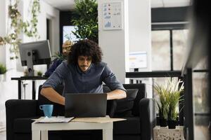 ung arab entreprenör analyserar företag försäljning statistik på bärbar dator medan arbetssätt i företag kontor. Start upp anställd hantera projekt och kontroll företags- marknadsföring forskning foto