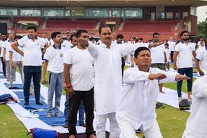 ny delhi, Indien, juni 21, 2023 - grupp yoga övning session för människor på yamuna sporter komplex i delhi på internationell yoga dag, stor grupp av vuxna delta yoga klass i cricket stadion foto