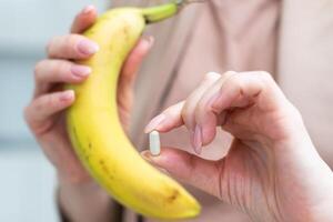kvinna innehav i händer ojämn bananer och piller foto