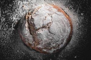 mörkt hembakat bröd pudrat med mjöl foto