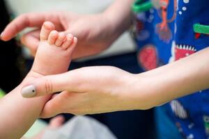 barnläkare granskning liten bebis i klinik. närbild av en barnets ben i läkares händer. foto