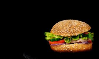 utsökt burger med kött och färsk grönsaker isolerat på svart bakgrund. ett gott nötkött aptitretande hamburgare. Plats för text foto