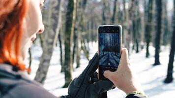 ung kvinna med handskar tar snö bilder med henne telefon foto