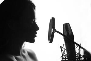 svart och vit. kvinna sång i de inspelning studio. profil av en kvinna med en skön ansikte och mun. foto