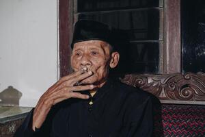porträtt av ett äldre asiatisk man rökning en cigarett. foto
