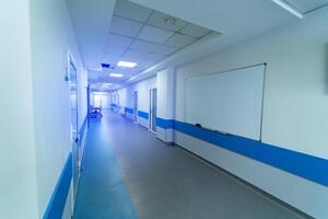 lång sjukhus hall i ljus vit och blå färger. många dörrar och whiteboard på vägg. foto