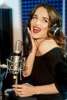 drömmande skön modell med hörlurar, innehav de mikrofon i musik studio. fantastisk kvinna sångare inspelning en Spår i en studio. foto